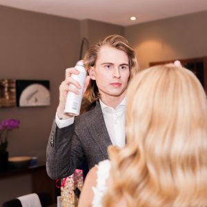A professional stylist adjusts a woman's hair.