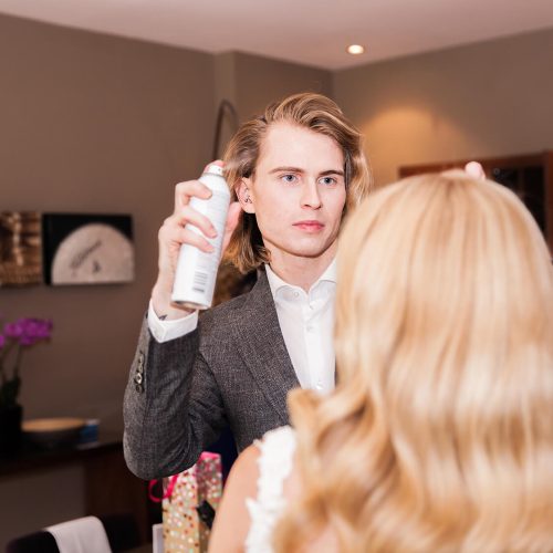 A professional stylist adjusts a woman's hair.